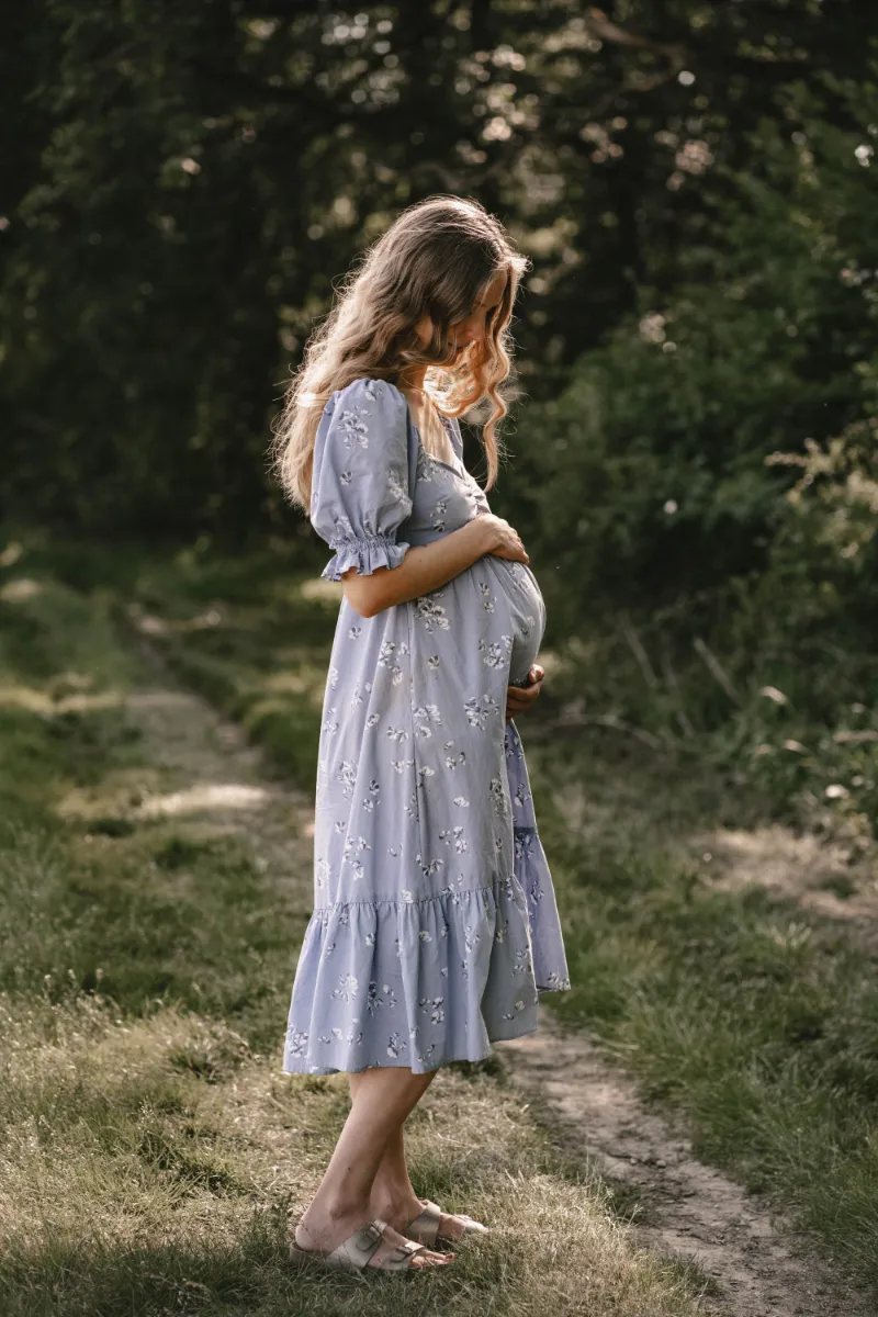 Schwangere Frau im blauen Blumenkleid Gegenlicht Sonne