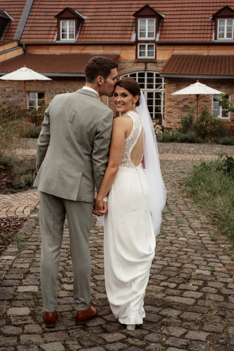 Brautpaar dreht Kamera Rücken zu Braut lächelt über die Schulter