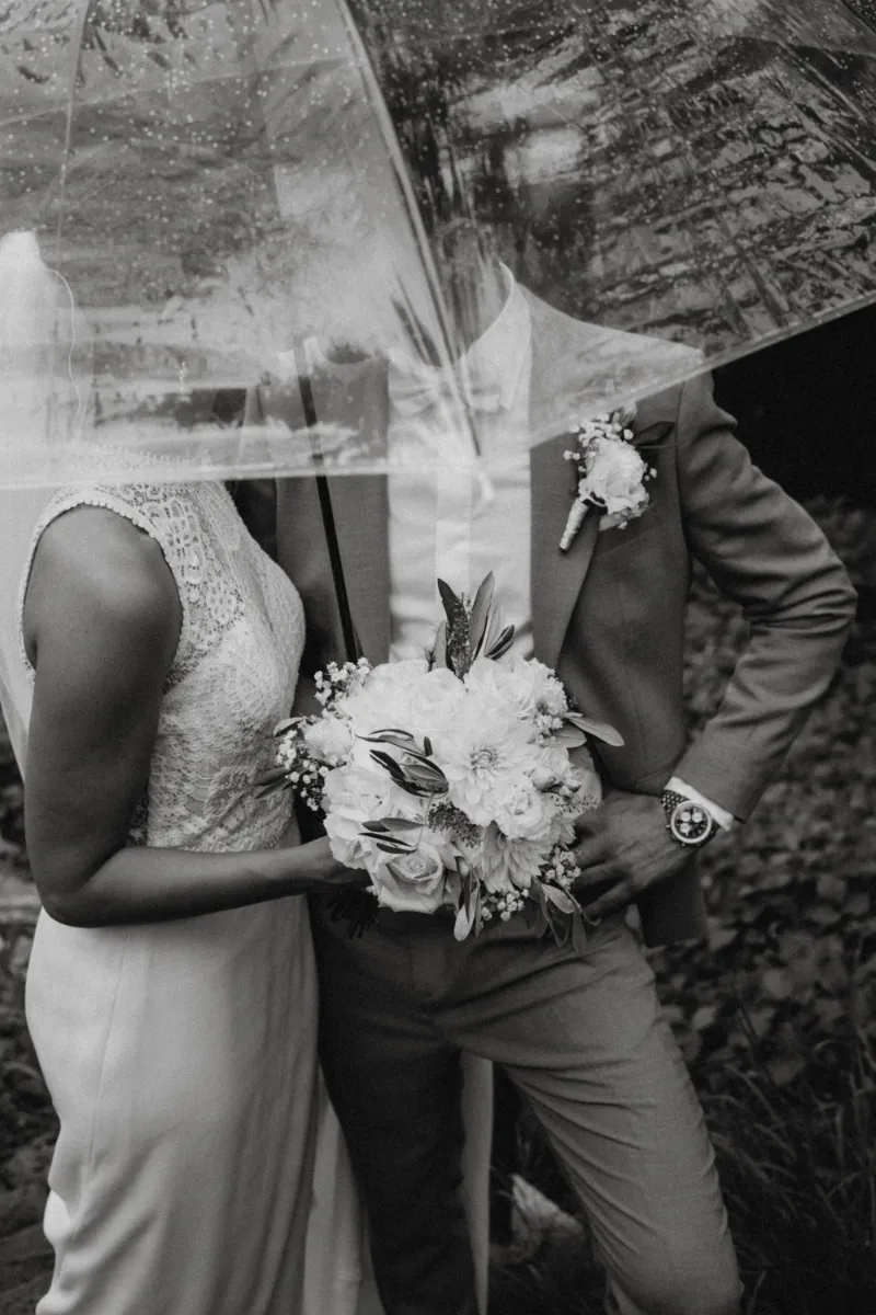 Brautpaar im Regen unter durchsichtigem Regenschirm