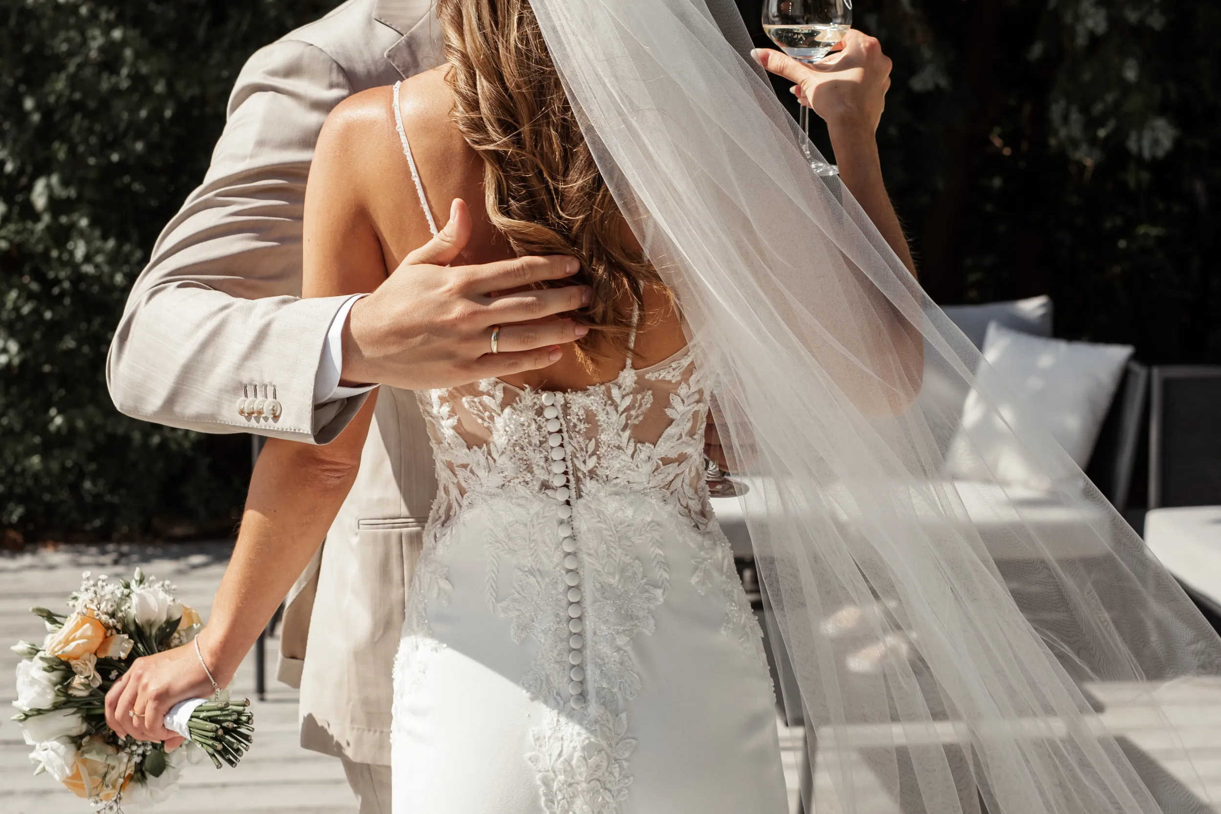 Nahaufnahme Brautpaar umarmt sich mit Glas Sekt in der Hand