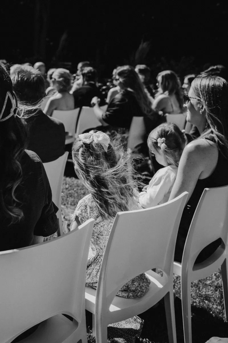 Gäste von hinten in Stuhlreihe sitzend warten auf Beginn der Trauung