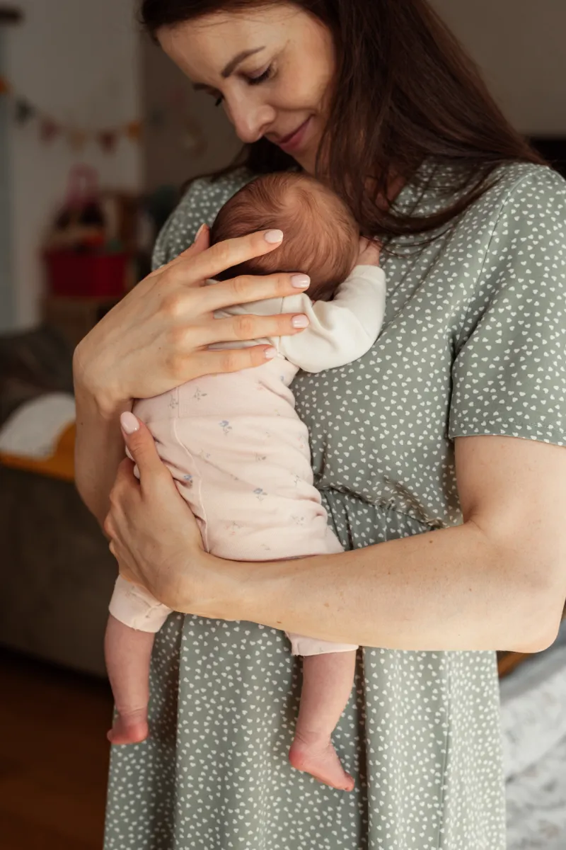 Mama trägt schlafendes Neugeborenes auf auf der Brust