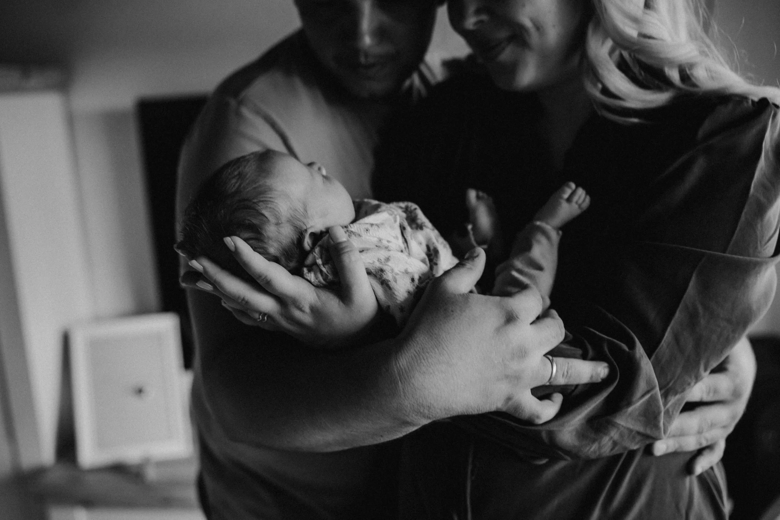 Mama und Papa halten Neugeborenes im Arm